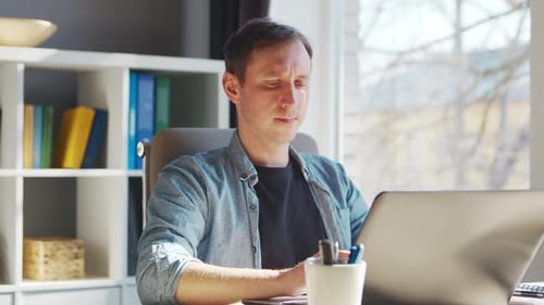 Young male entrepreneur works at home office at the computer.