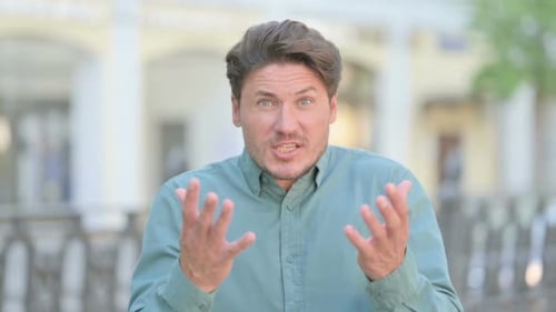 Man Gesturing and Talking Outdoors in Daylight