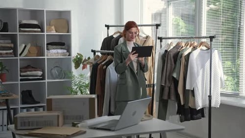 Retrato de jovem empresário com tablet em suas mãos está fazendo um inventário de roupas nas prateleiras