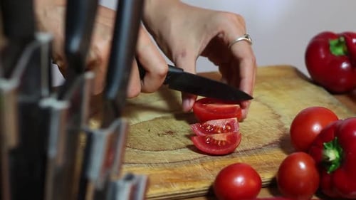Hands Slice Tomato on Wooden Cutting Board
