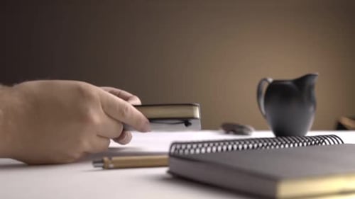 Hand Writes in Notebook on White Desk