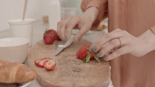 Woman Cuts Strawberry on Wooden Cutting Board