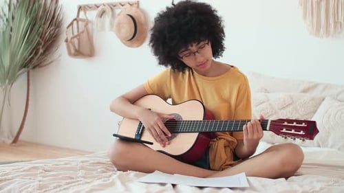 Woman Plays Guitar in Bedroom