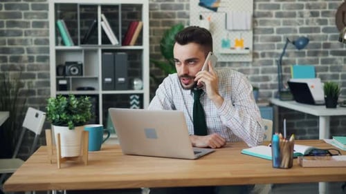 Man Talks on Phone at Desk in Office