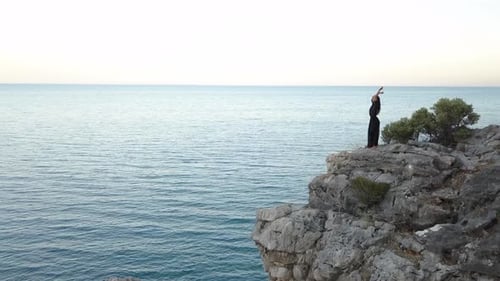 Aerial View of Young Woman on Rock Cliff Against Sea