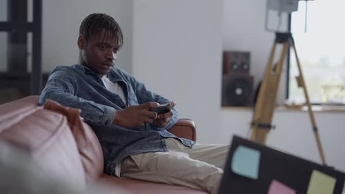 Young Adult Relaxing on Couch Using Mobile Phone