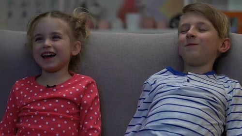 Smiling Girl and Boy Laughing on a Gray Couch