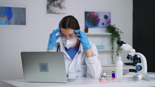 Doctor with Head in Hands at Desk