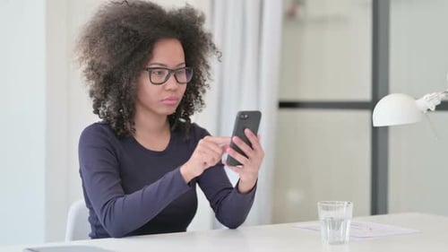 Focused Young Adult Using Phone at Desk Indoors