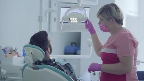 Dentist in Medical Mask and Gloves Checking the Mouth of the Patient Using Medical Tools in a Modern