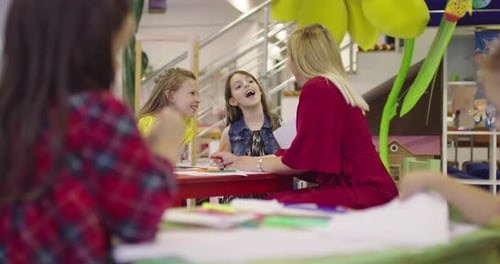 In Primary School Children Drawing in the Classroom with a Female Teacher Together Playing Smiling