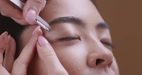 Woman Having Eyebrows Shaped with Tweezers Close Up