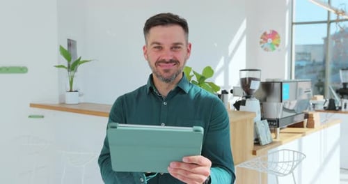 Young Successful Cafe Owner Standing in Cafe Using Digital Tablet While Accepting Online Order