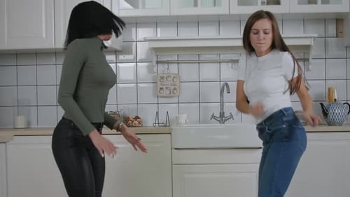Two Young Women Dancing Together in a Kitchen