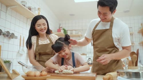 Asian happy family spending time in kitchen together while staying at home doing homemade bakery.