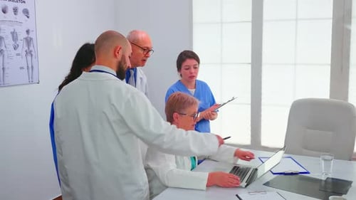 Medical Professionals Collaborating Around a Laptop in Office