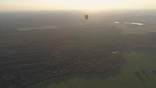 Hot Air Balloon Flying Over Field at Sunrise