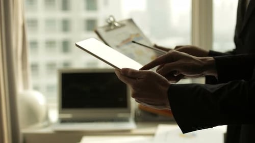 Business People Reviewing Data on Tablet and Clipboard