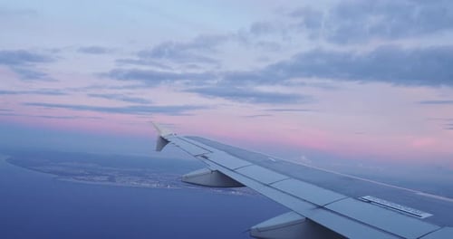 Airplane Flying at Sunset over City Coastline