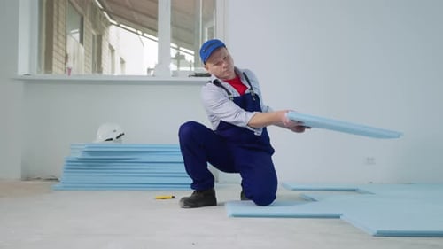 Man Laying Blue Insulation Panels on Floor