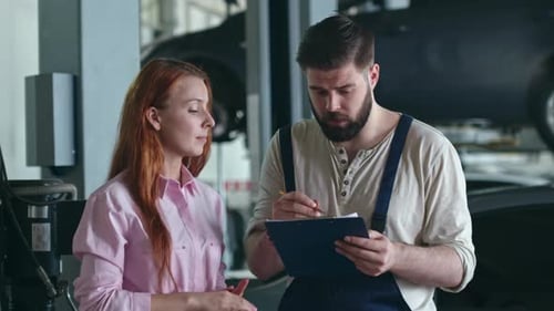 Woman Speaking to Mechanic in Car Repair Shop