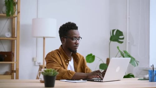Man Typing on Laptop at Desk Indoors