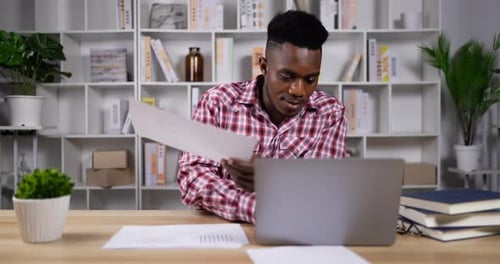 Adult Reviews Documents at Desk in Home Office