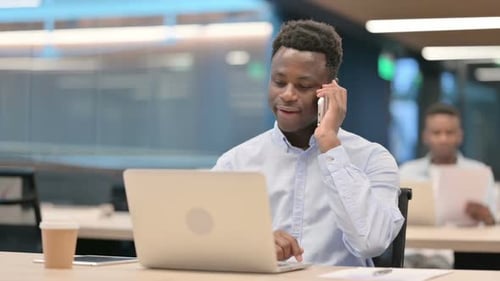 Young Adult Talks on Phone and Uses Laptop