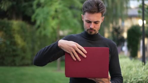 Man Opens Laptop in Verdant Green Park