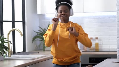 Woman Dancing with Headphones in Kitchen