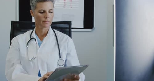 Smiling Doctor Using Tablet Computer in Office