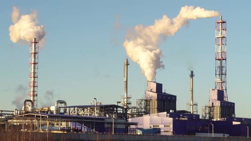 Industrial Complex Emitting Smoke Against Clear Sky