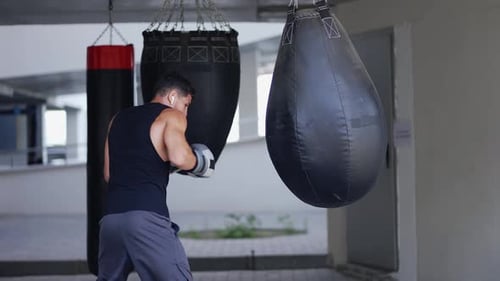 Man Boxing Heavy Bag in an Urban Gym