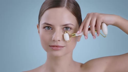 Portrait of Seductive Woman Using Facial Massage Roller and Smilling While Looking to Camera