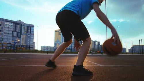 Young Man Training with a Basketball on the Court at Sunset Cinematic Shot