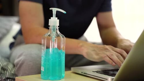 Man Cleans Hands While Working at Computer