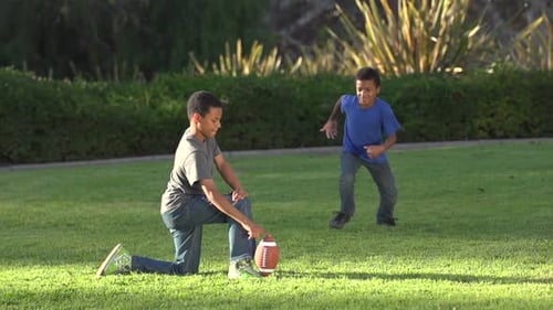 Boys Kicking Football on Grassy Suburban Lawn