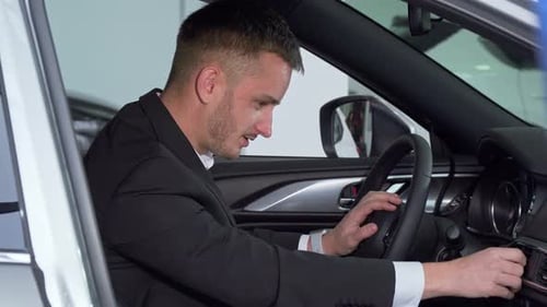 Man in Suit Adjusts Car Settings in Showroom