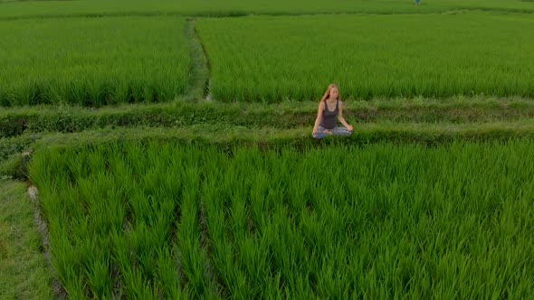 Aerial Shot of a Woman Meditating on a Marvelous Rice Field During ...
