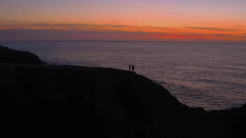 Silhouette of Couple Walk on Cliff Edge at Sunset