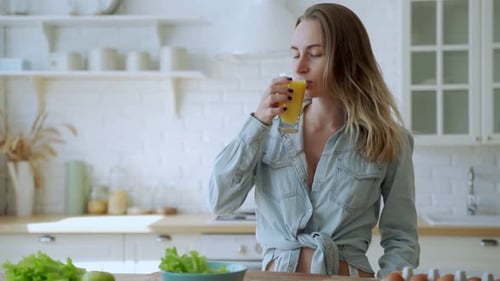Woman Enjoying Juice in Bright, Modern Kitchen
