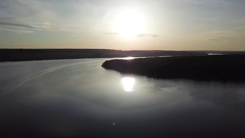 Magnificent view of the river with the reflection of the sun in it from aerial view.
