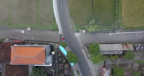 Aerial drone view of a man riding his motocross motorcycle on a road in Bali