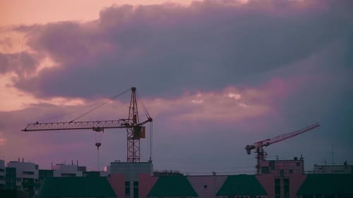 Construction Cranes Silhouetted at Colorful Sunset
