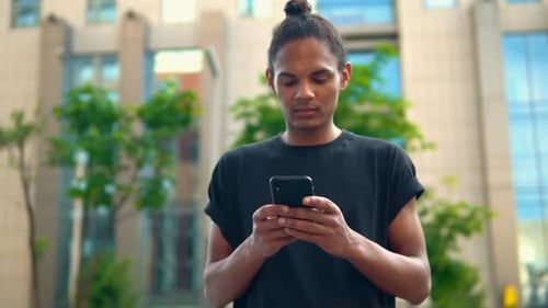 Mixed Race Guy Typing Message on Mobile on the Run