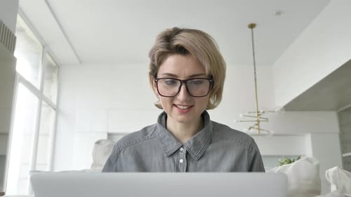 Smiling Woman Working on Laptop in Bright Office