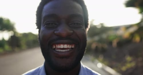 Young african man smiling on camera in the city with sunset in the background