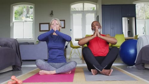 Mature Couple Performing Yoga in Brightly Lit Room