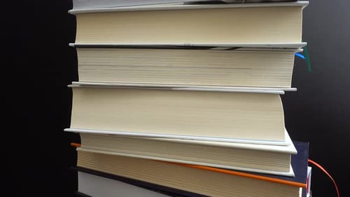 Stack of Hardcover Books Against Dark Background