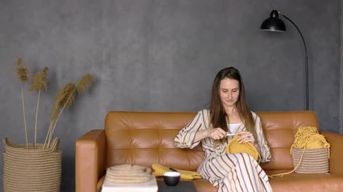 Woman Crocheting Yellow Yarn on Couch Indoors